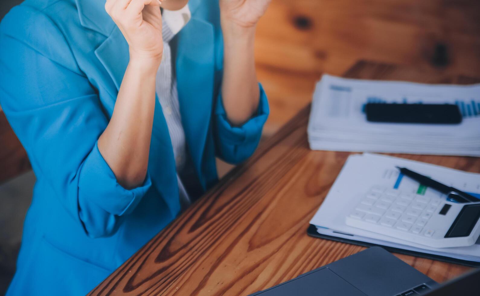Asian Business woman using calculator and laptop for doing math finance on an office desk, tax, report, accounting, statistics, and analytical research concept photo