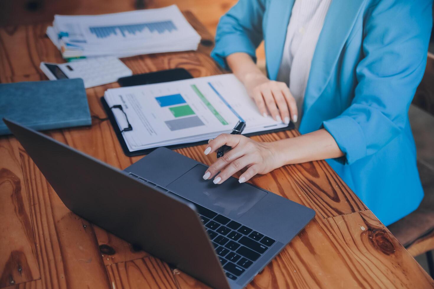 Asian Business woman using calculator and laptop for doing math finance on an office desk, tax, report, accounting, statistics, and analytical research concept photo