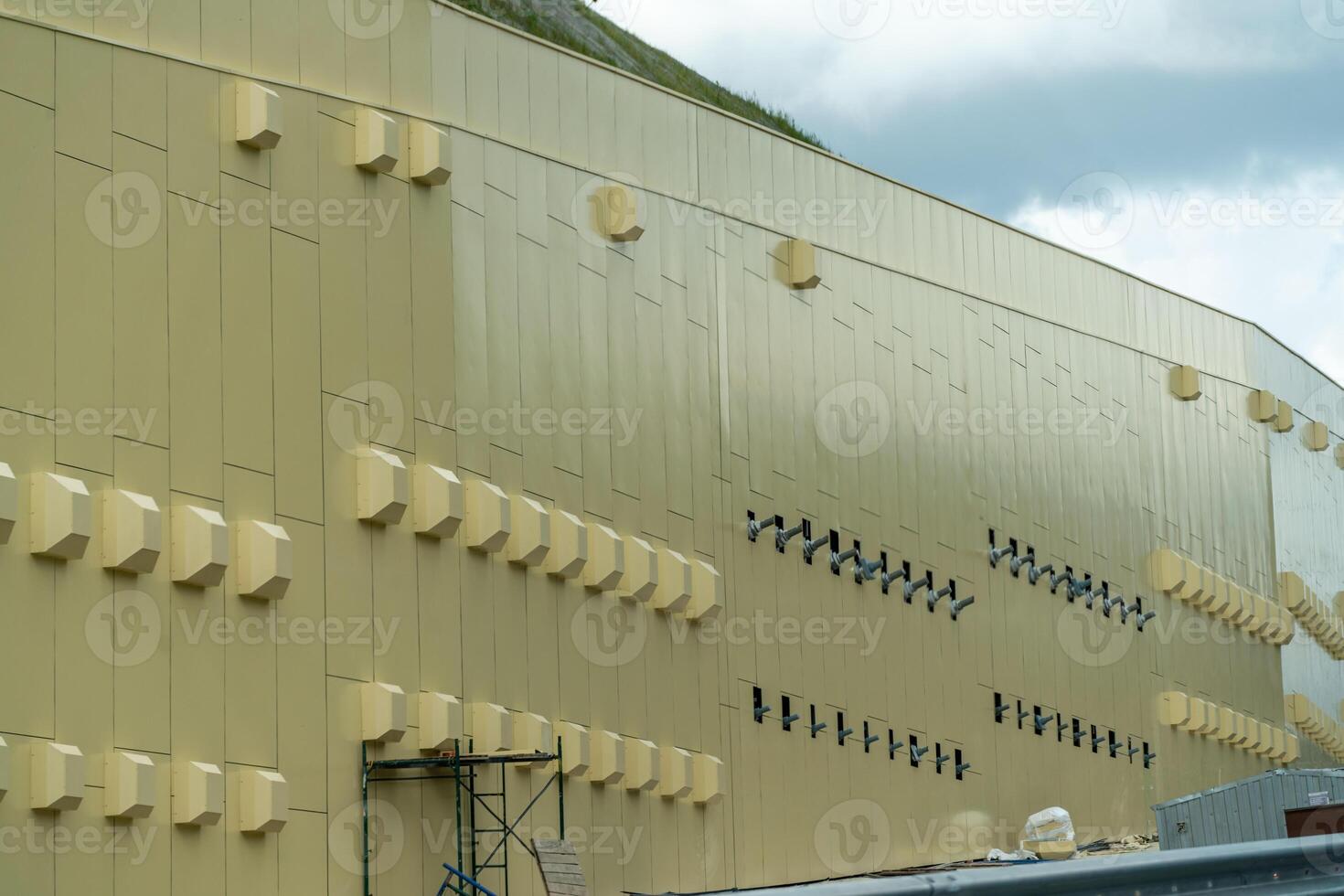A large building with many windows and vents. The building is yellow and has a lot of windows. photo
