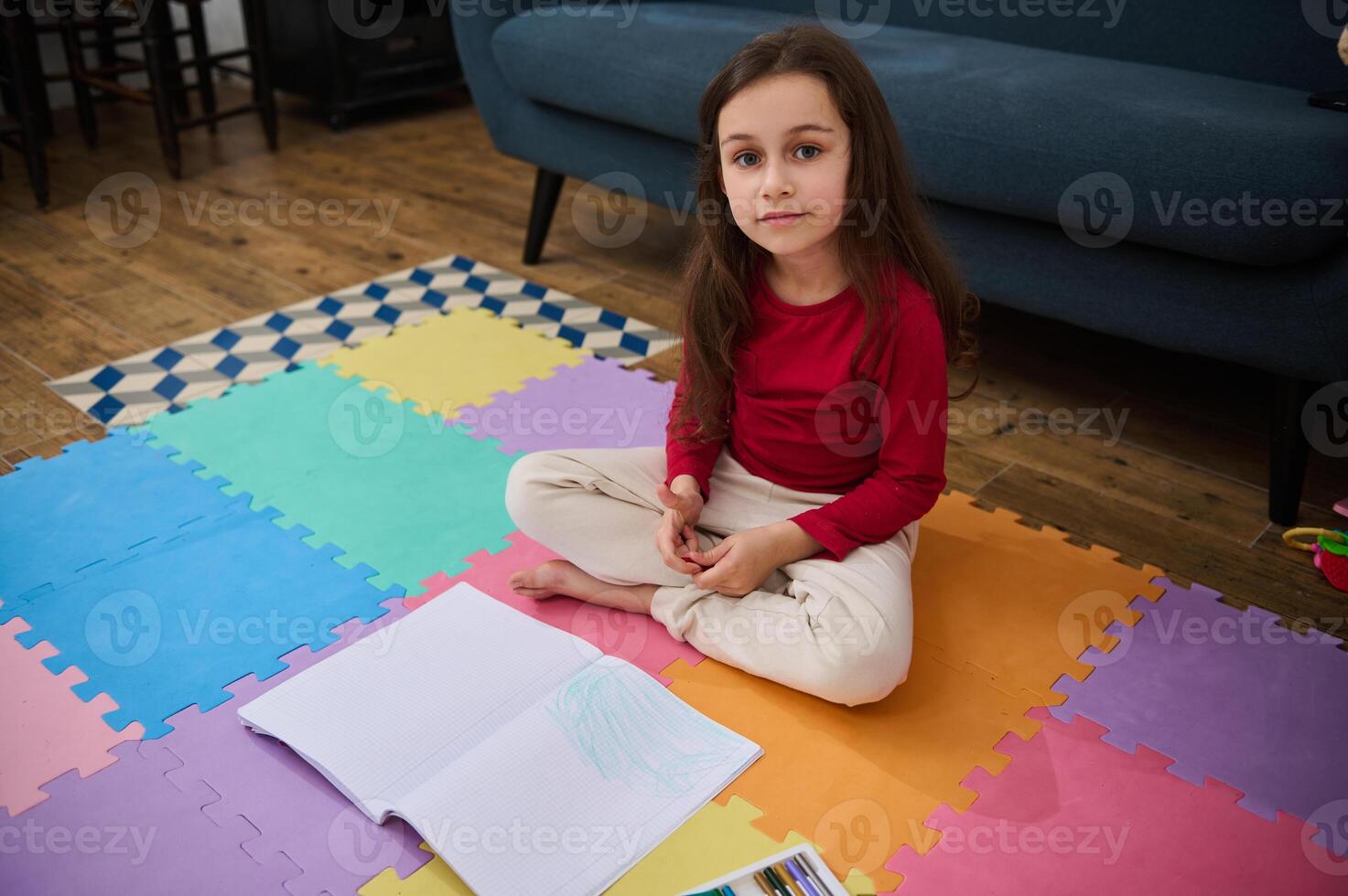 Adorable elementary age child, little school girl at home, doing homework, writing on copy book, smiling looking at camera photo