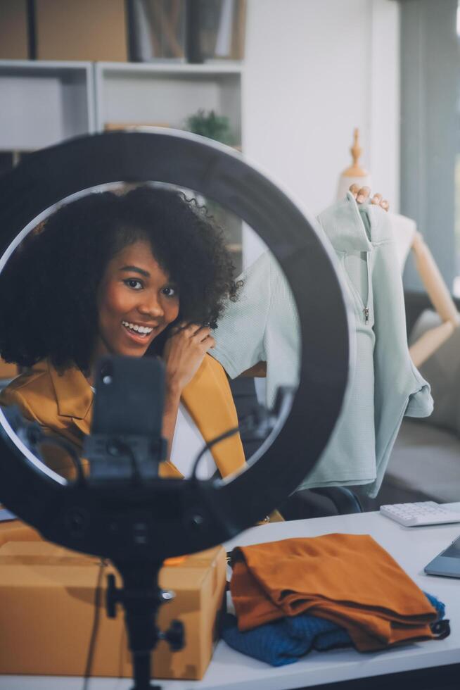 Fashion blogger concept, Young Asian women selling clothes on streaming.Startup small business SME, using smartphone or tablet taking receive and checking in office photo
