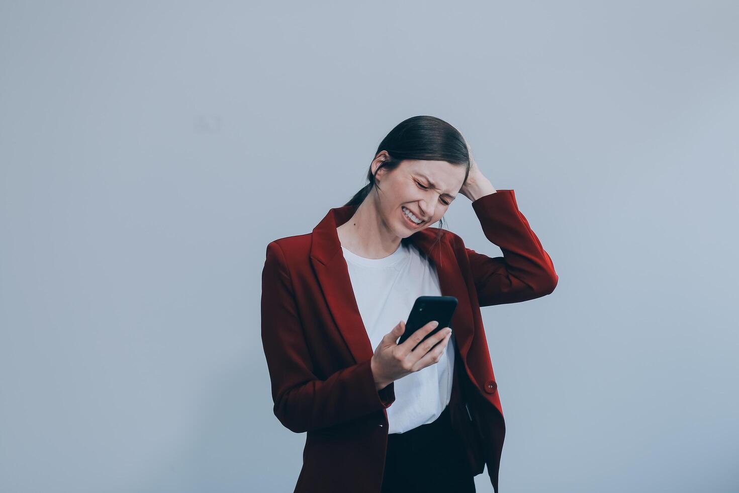 irritado enojado joven mujer enojado acerca de correo no deseado mensaje atascado teléfono mirando a teléfono inteligente aislado en blanco estudio fondo, furioso adolescente niña teniendo problema con Teléfono móvil irritado por roto móvil foto