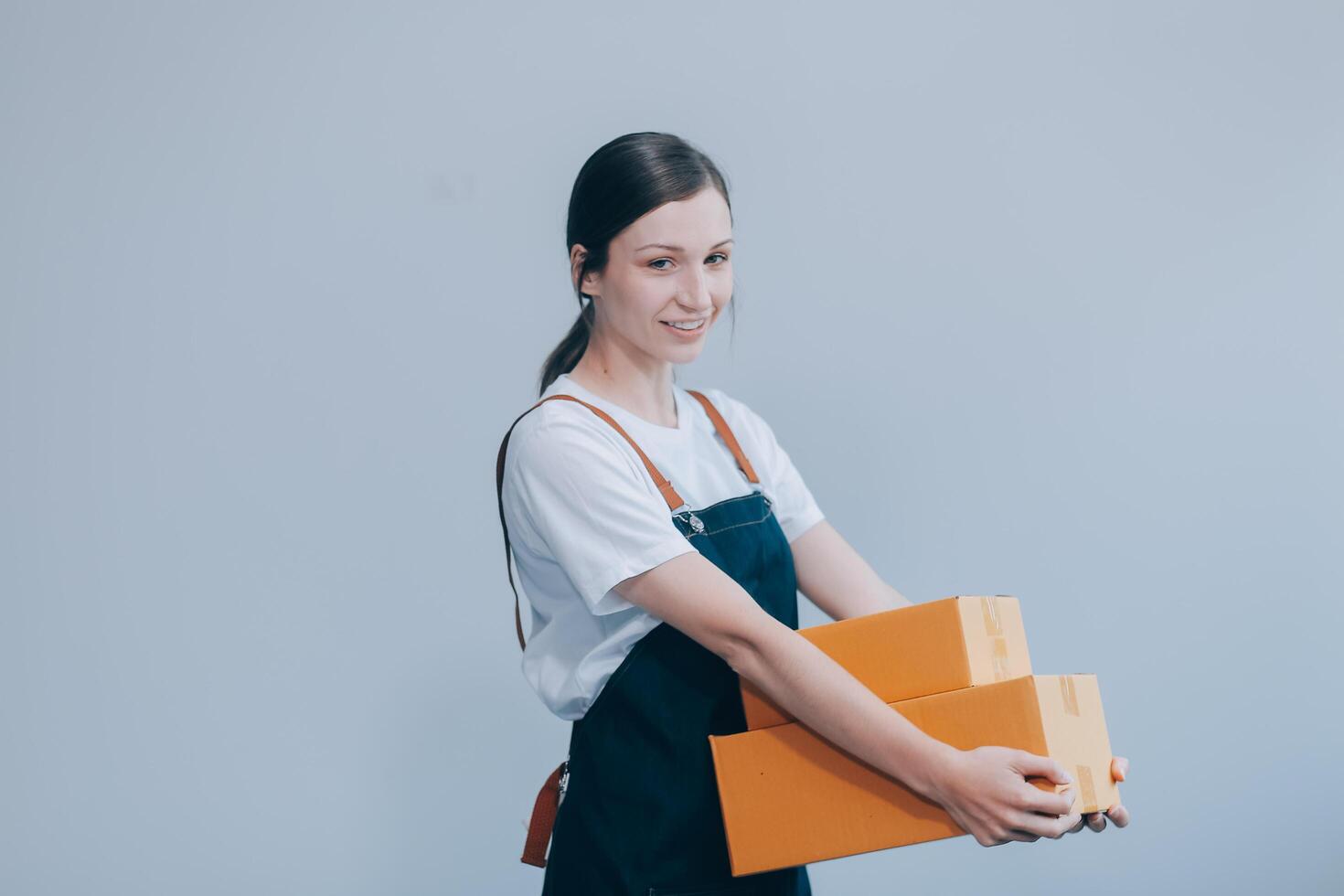 Smiling Asian woman in casual clothes holding a cardboard box mockup while standing against an isolated white background. shipping business concept photo