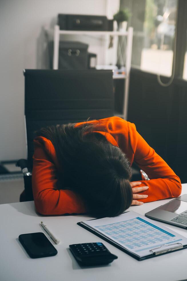 Portrait of tired young business Asian woman work with documents tax laptop computer in office. Sad, unhappy, Worried, Depression, or employee life stress concept photo
