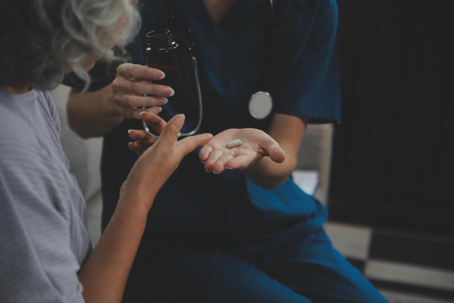 Female caregiver doing regular check-up of senior woman in her home. photo