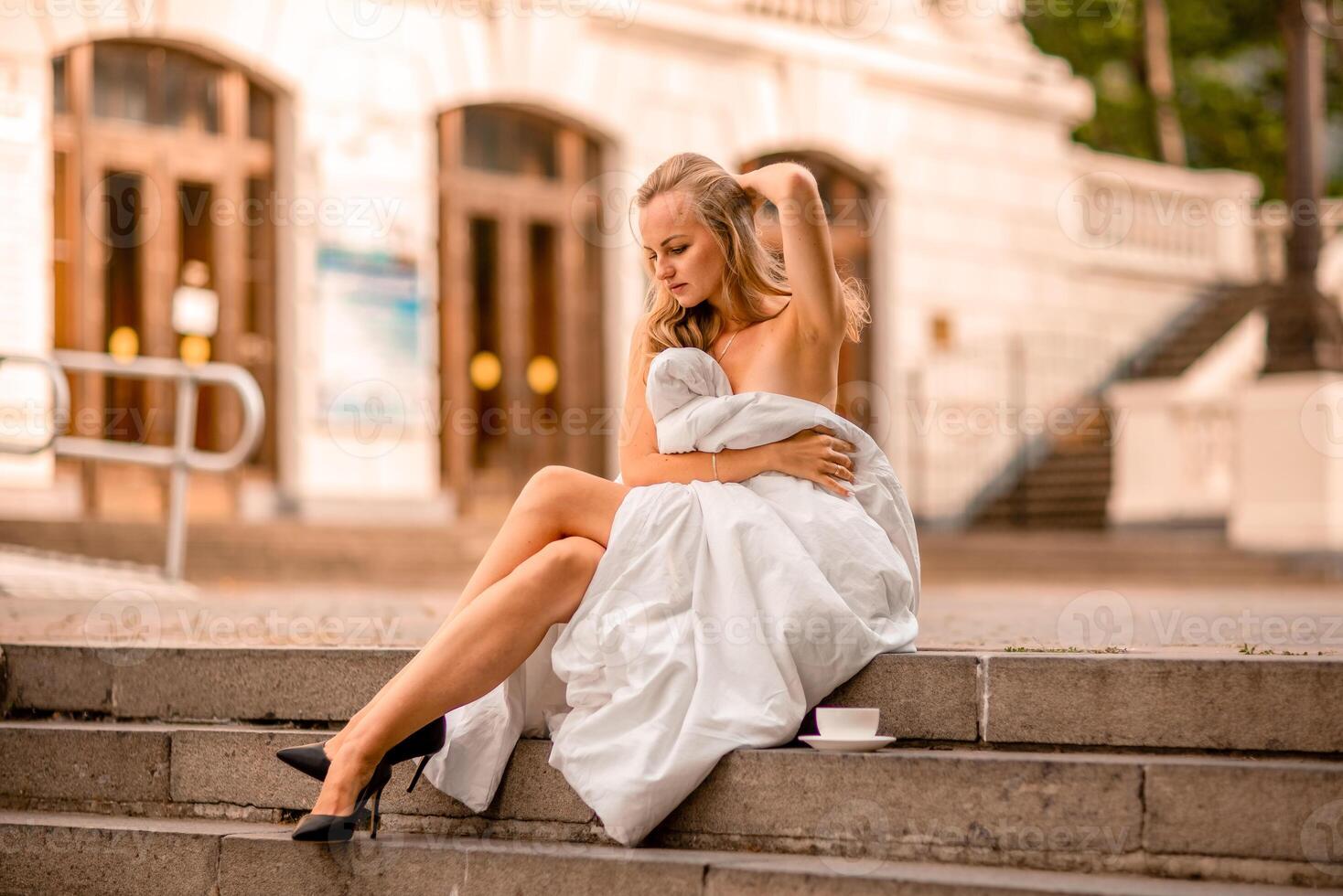 Woman city blanket. Morning in the big city. A blonde woman in a white blanket is enjoying in the city center. Photographed for social media photo