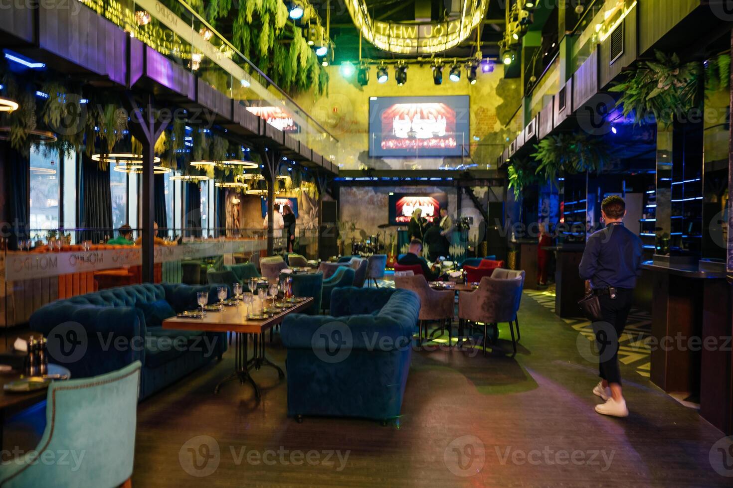 A restaurant with a large screen TV and a lot of seating. The TV is showing a game. photo