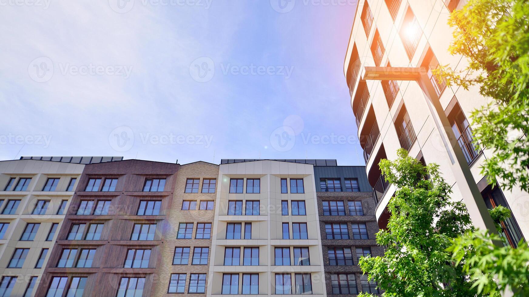 Modern residential building with new apartments in a green residential area. Eco architecture. Green tree and new apartment building. The harmony of nature and modernity. photo