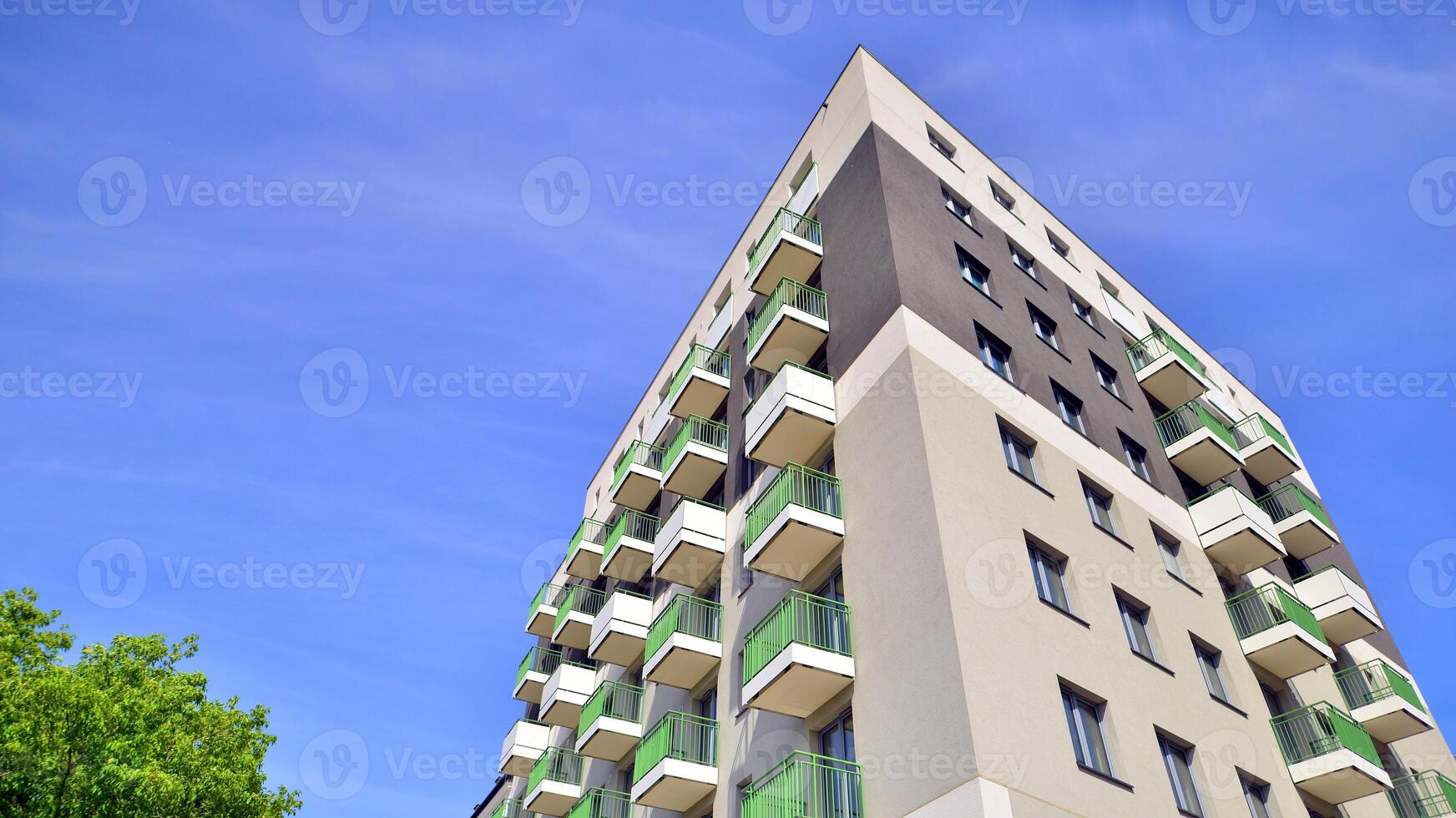 Modern residential building with new apartments in a green residential area. Eco architecture. Green tree and new apartment building. The harmony of nature and modernity. photo
