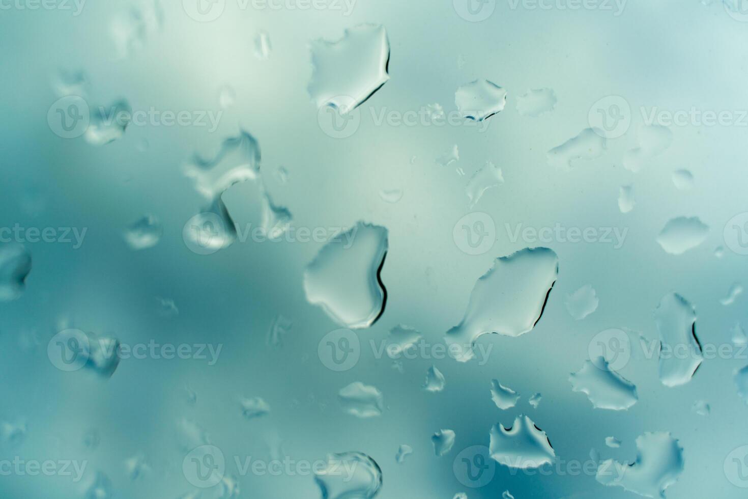 Water drops on glass against blue sky, rainy season concept. Window view background screensaver photo
