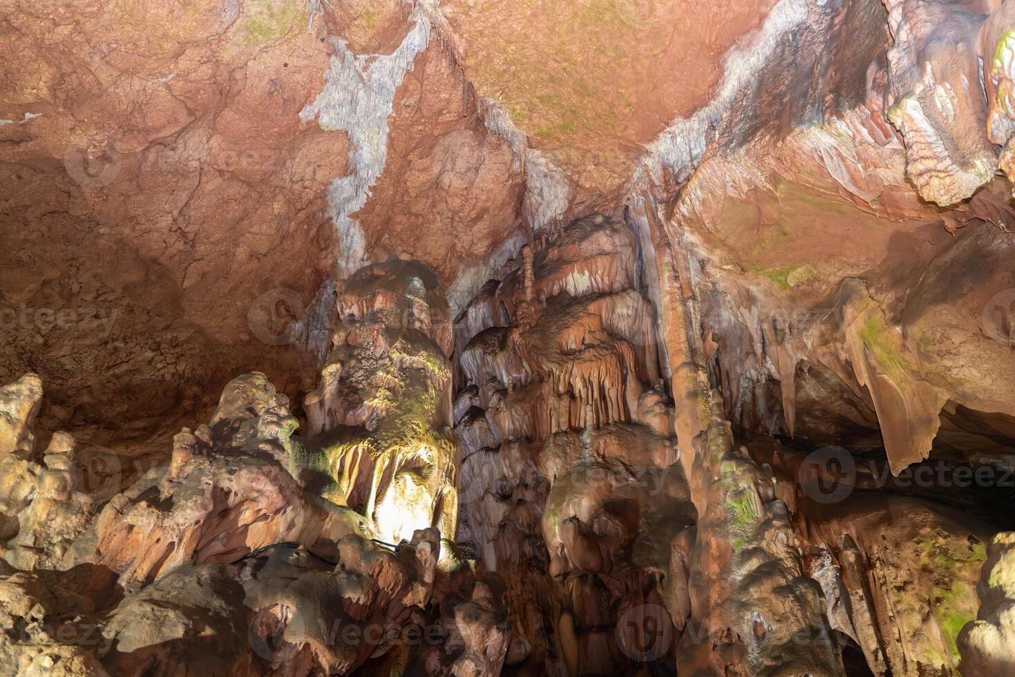 The cave is dark and damp, with moss growing on the walls. The ceiling is made of rocks and the floor is covered in dirt. photo