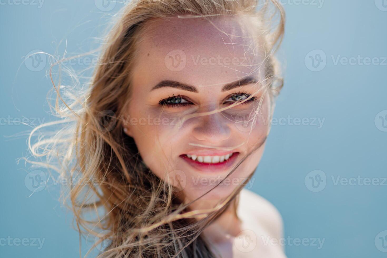 Portrait of a blond woman at the sea, a woman makes photos for memory from a trip to the sea to show to friends.