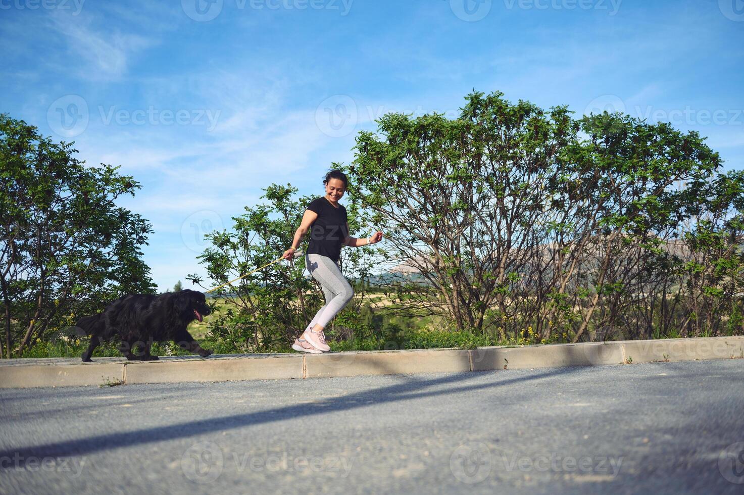 Young active woman jogging with her dog as a fun way to exercise in the nature outdoors. People. Animals. Nature. Active and healthy lifestyle concept. photo