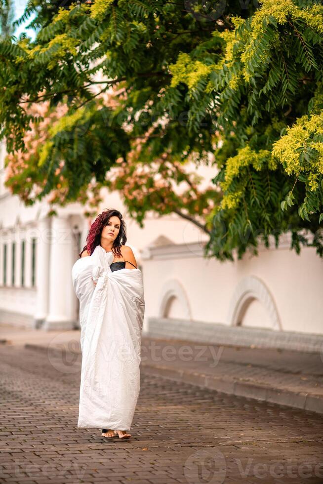 Woman city blanket. Morning in the big city. A blonde woman in a white blanket is enjoying in the city center. Photographed for social media photo