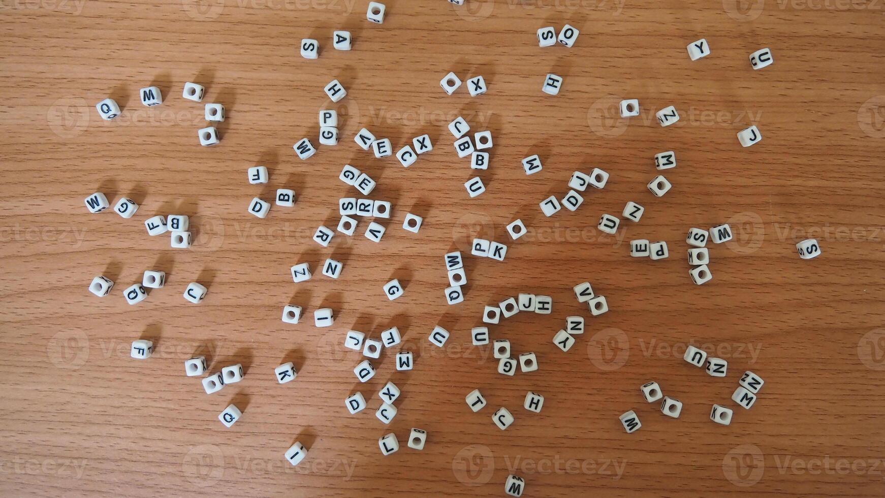 alphabet white beads blocks with letters in heart, random letters around, top view wooden background backdrop photo