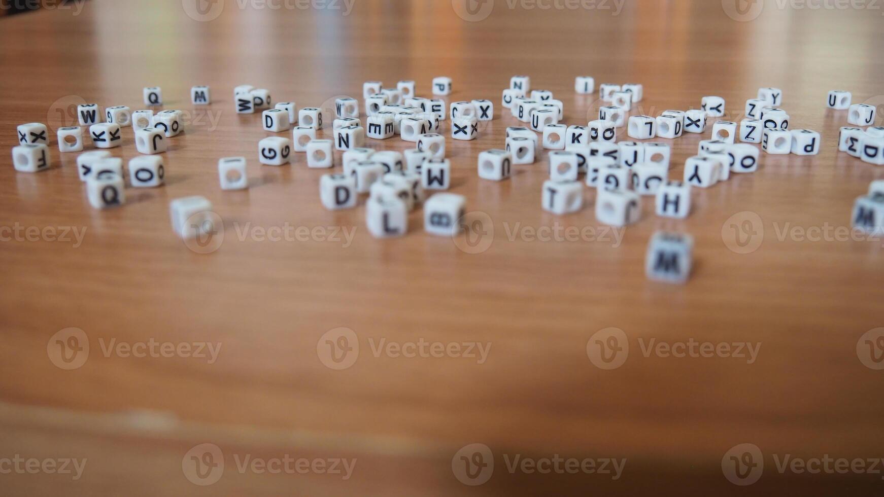 alphabet white beads blocks with letters in heart, random letters around, top view wooden background backdrop photo