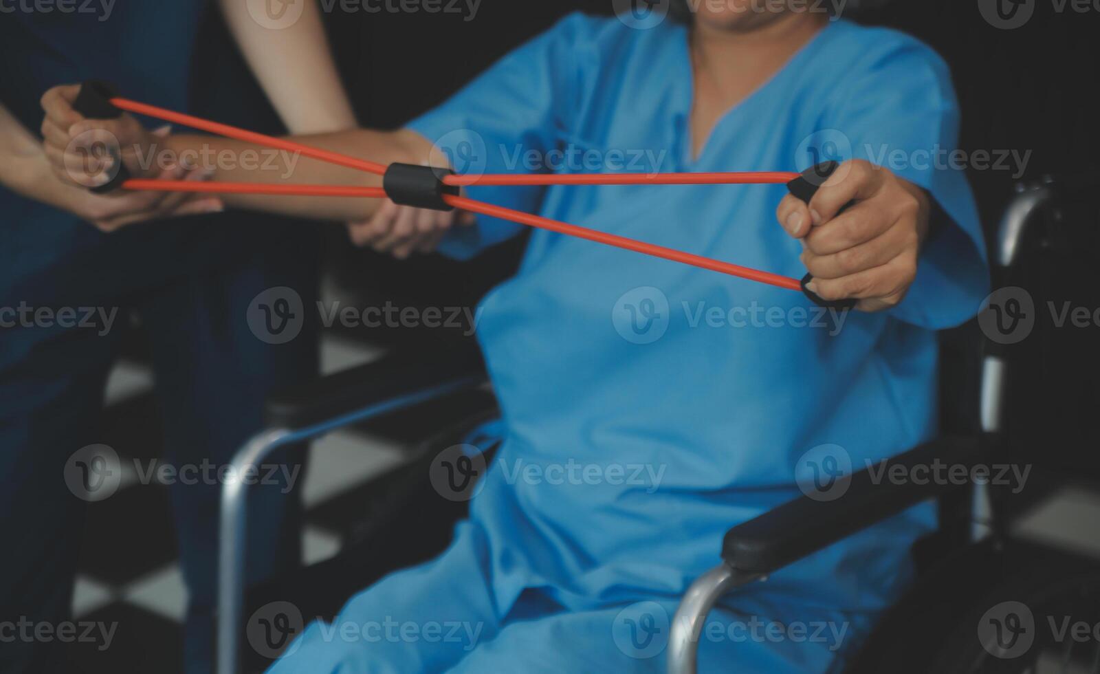 Personal trainer assisting senior woman with resistance band. Rehabilitation physiotherapy worker helping old patient at nursing home. Old woman with stretch band being coached by physiotherapist. photo