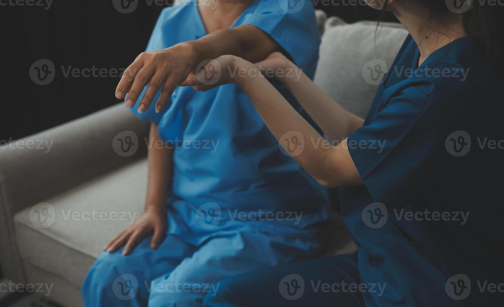 Old woman training with physiotherapist using dumbbells at home. Therapist assisting senior woman with exercises in nursing home. Elderly patient using dumbbells with outstretched arms. photo