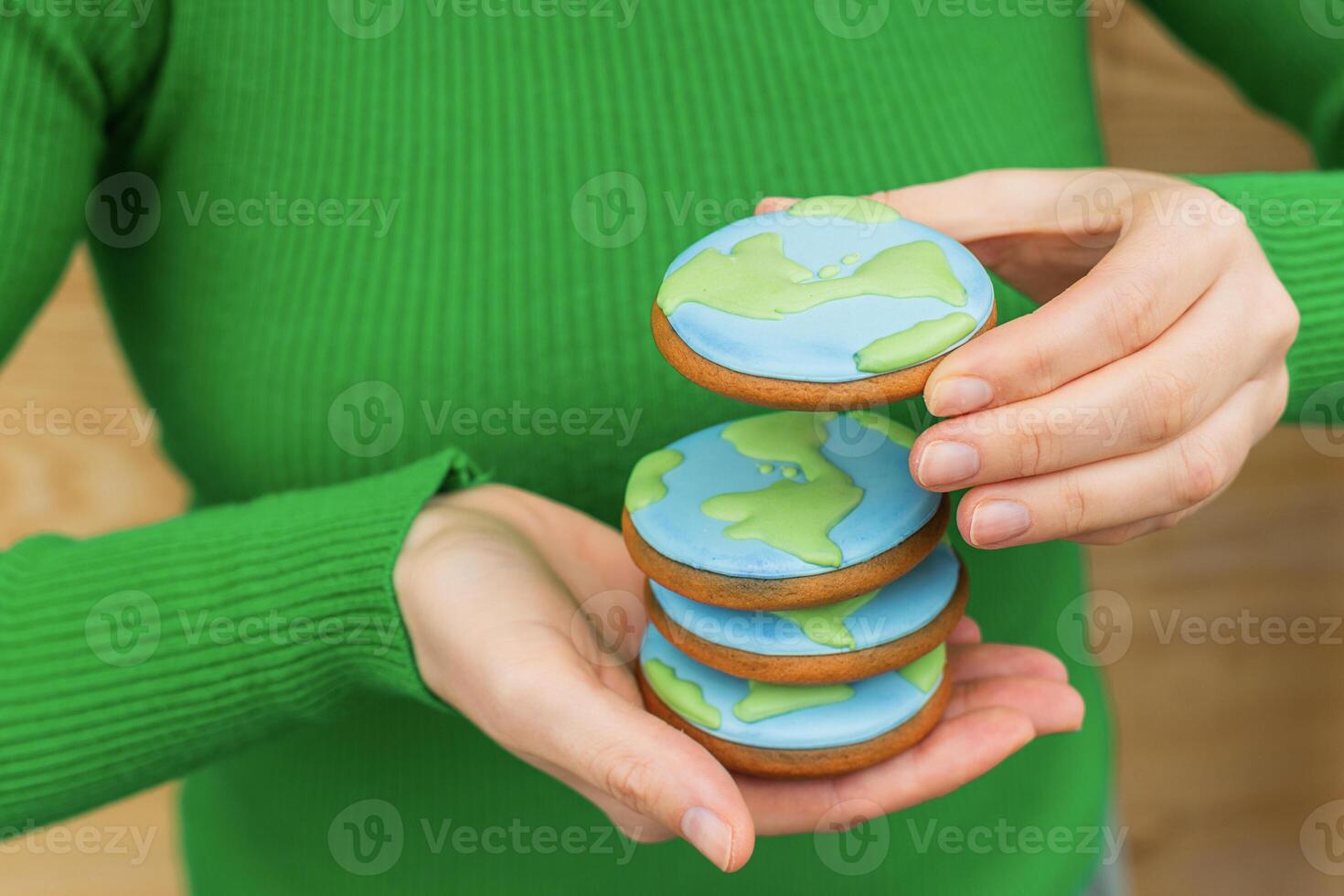 Earth Day concept. Stack of cookies in the shape of the Earth in female hands. photo