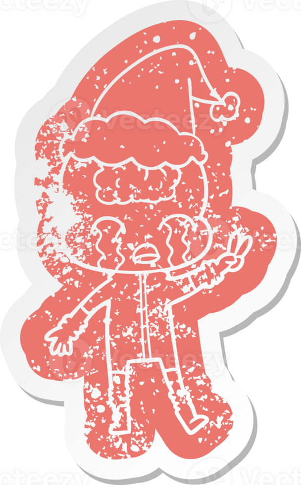 quirky cartoon distressed sticker of a big brain alien crying and giving peace sign wearing santa hat png