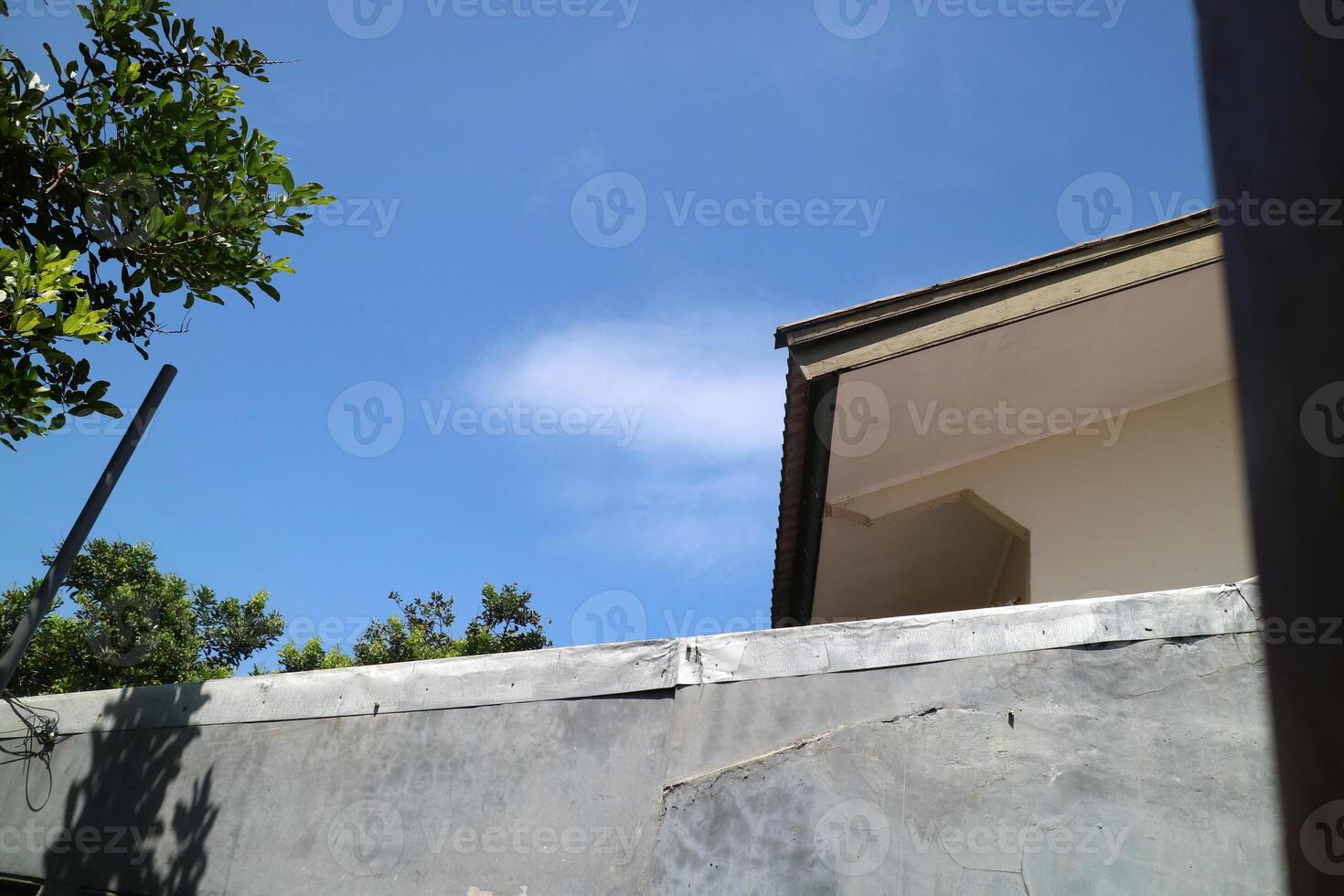 view of a house roof and walls with a view of the bright blue sky photo