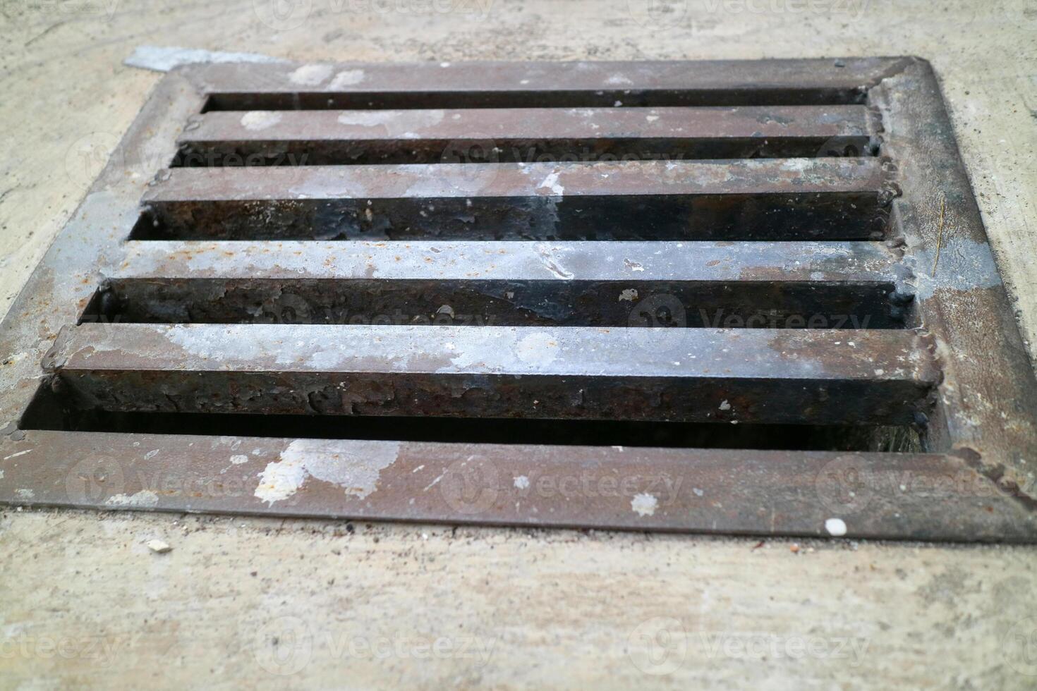 an iron gutter cover, with a rust color. Box shaped. on a concrete road photo