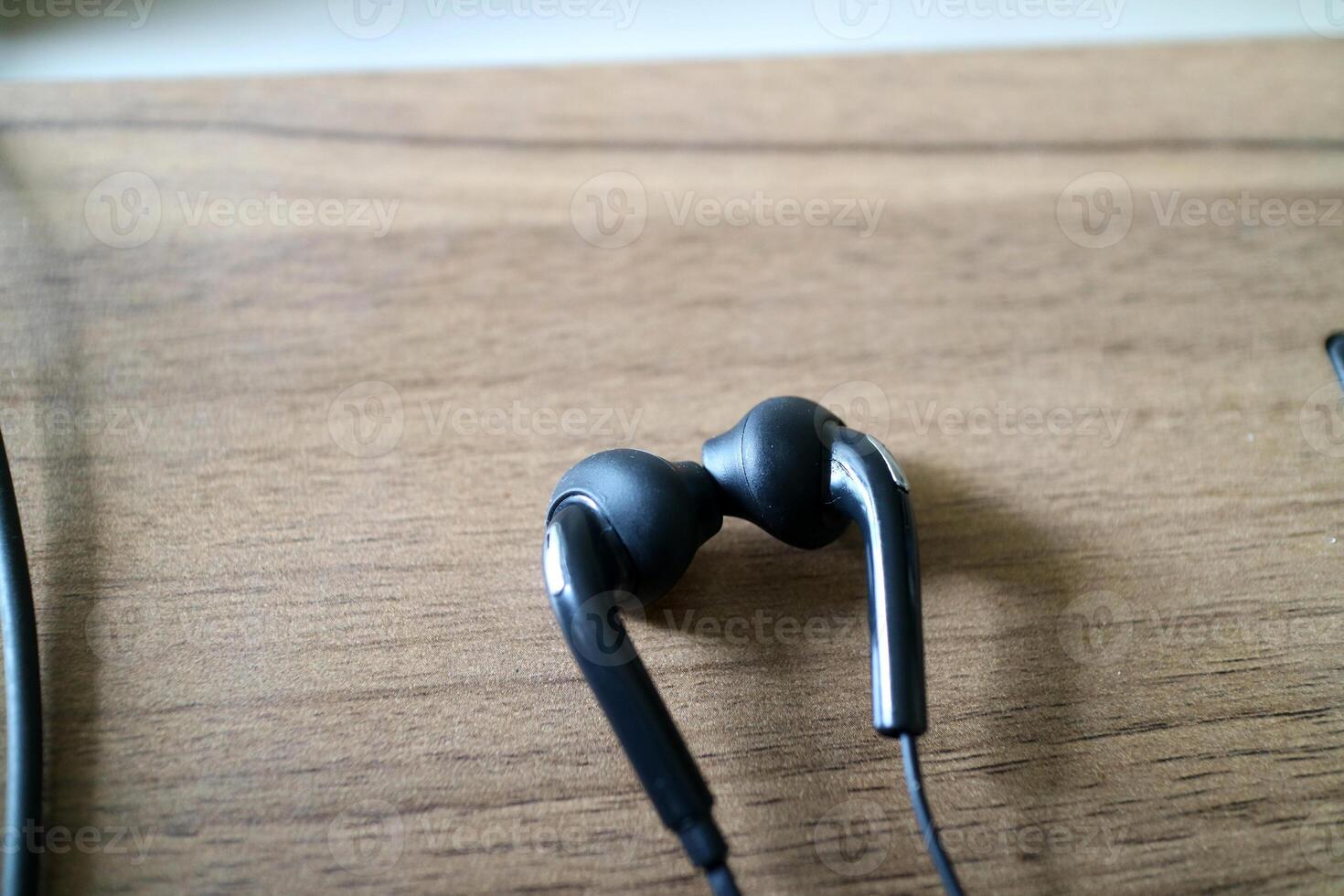 a pair of headsets with cables. black, placed on a table with a wooden motif photo