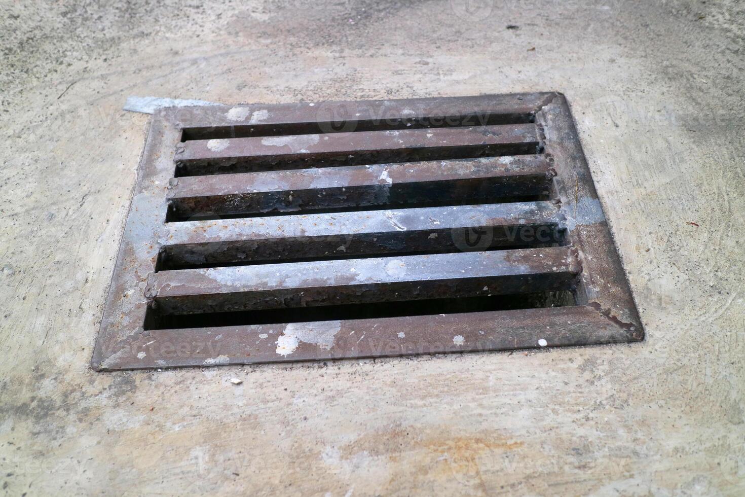 an iron gutter cover, with a rust color. Box shaped. on a concrete road photo