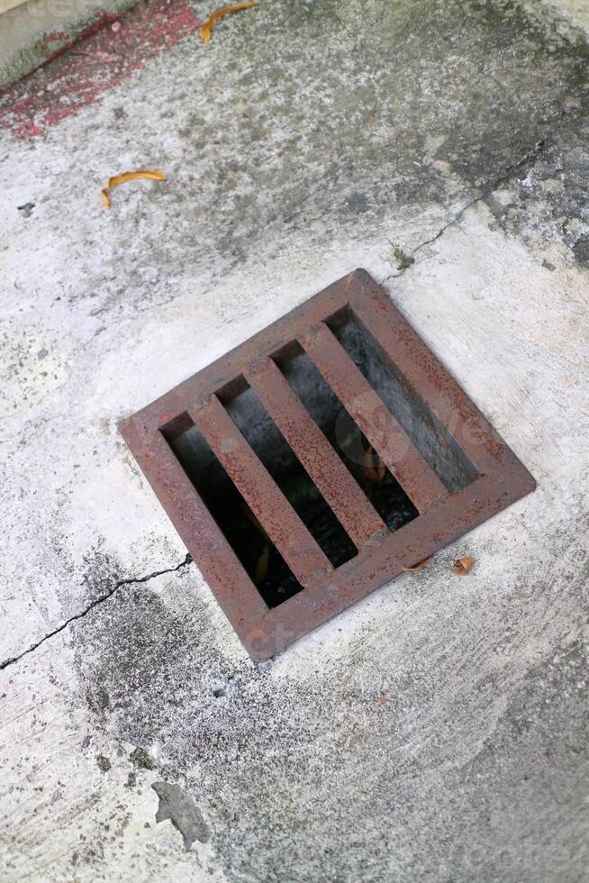 an iron gutter cover, with a rust color. Box shaped. on a concrete road photo