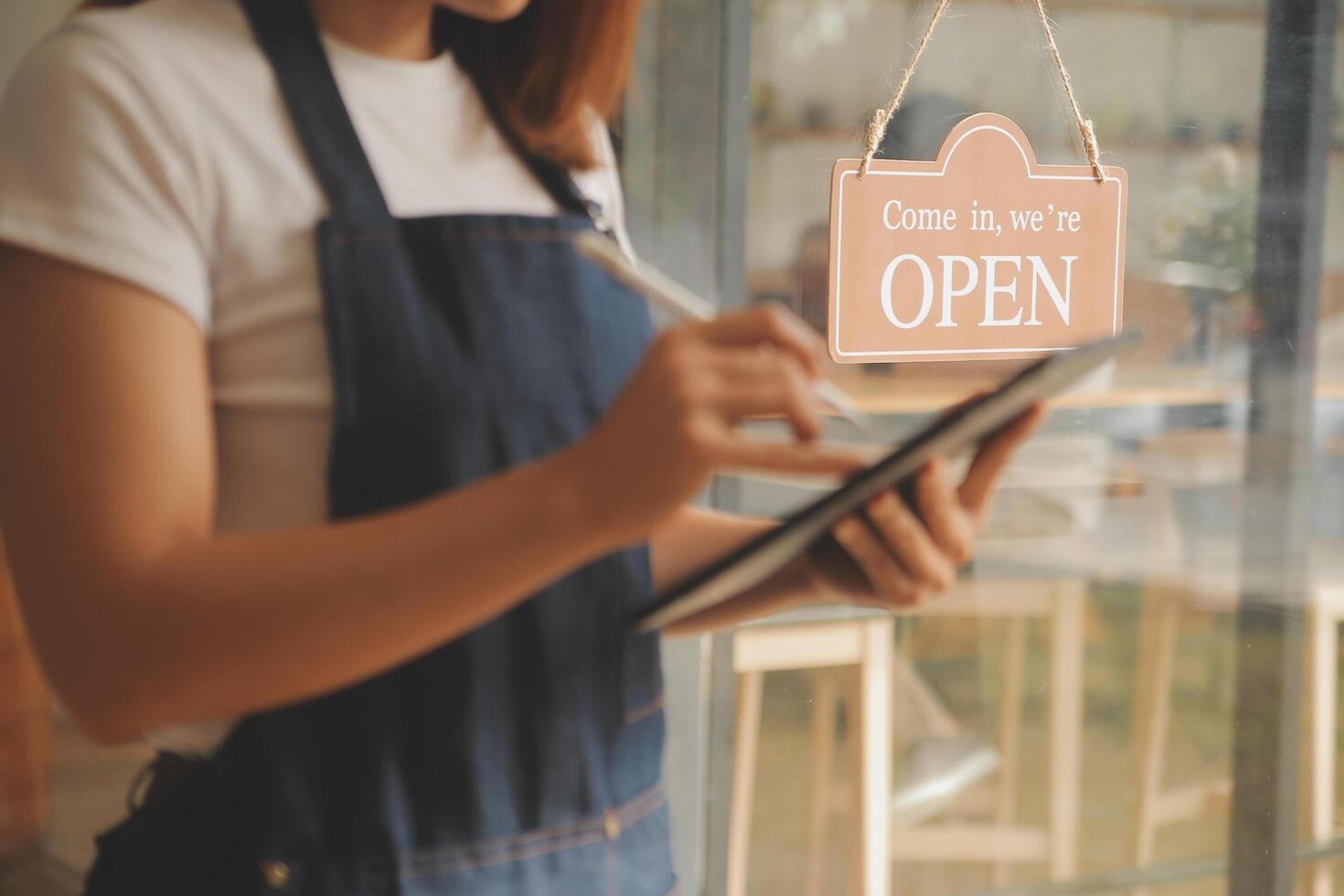 startup exitosa propietaria de una pequeña empresa sme beauty girl stand con tablet smartphone en cafetería restaurante. retrato de una mujer asiática bronceada barista dueña de un café. pyme empresario vendedor concepto de negocio foto