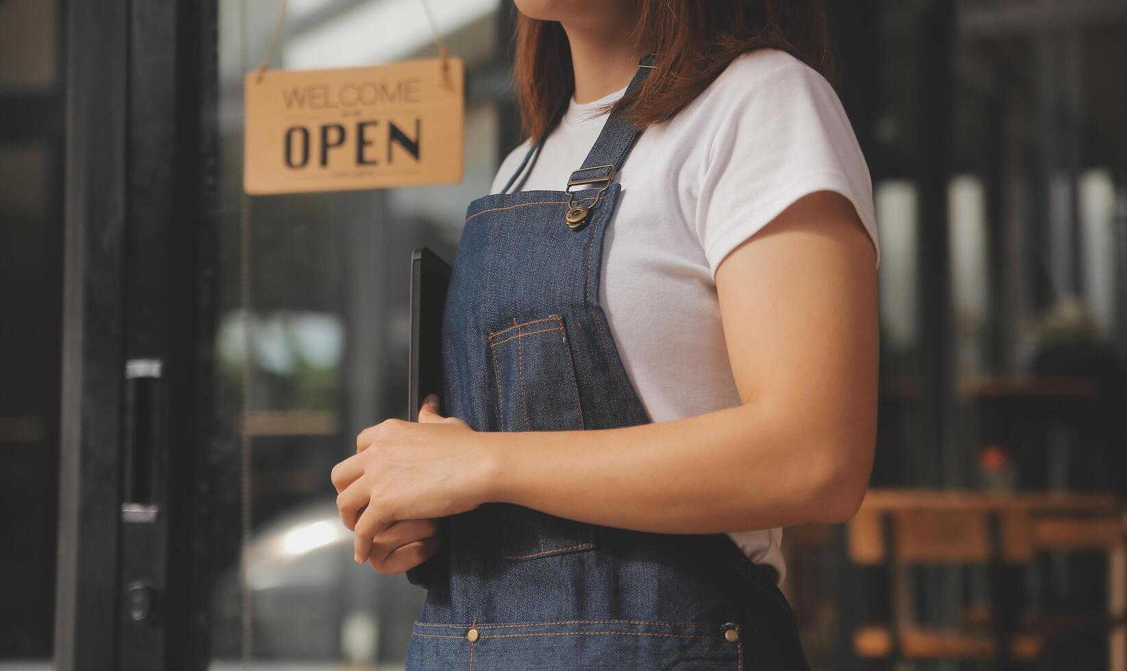 Startup successful small business owner sme beauty girl stand with tablet smartphone in coffee shop restaurant. Portrait of asian tan woman barista cafe owner. SME entrepreneur seller business concept photo