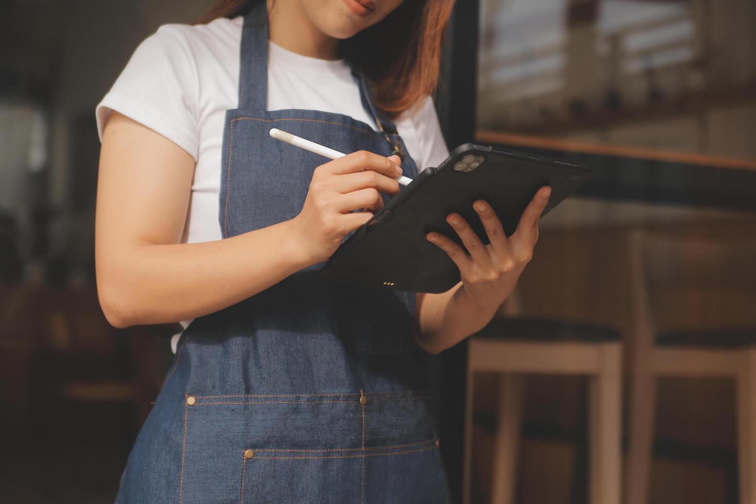 Startup successful small business owner sme beauty girl stand with tablet smartphone in coffee shop restaurant. Portrait of asian tan woman barista cafe owner. SME entrepreneur seller business concept photo