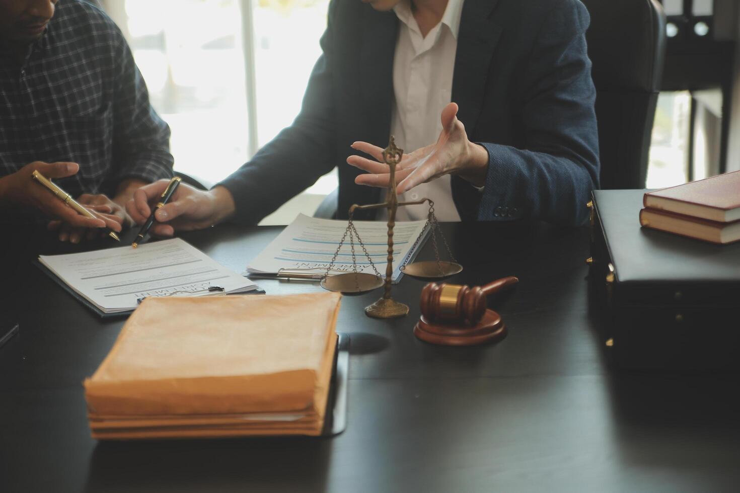 Justice and Law concept. Legal counsel presents to the client a signed contract with gavel and legal law or legal having team meeting at law firm in background photo