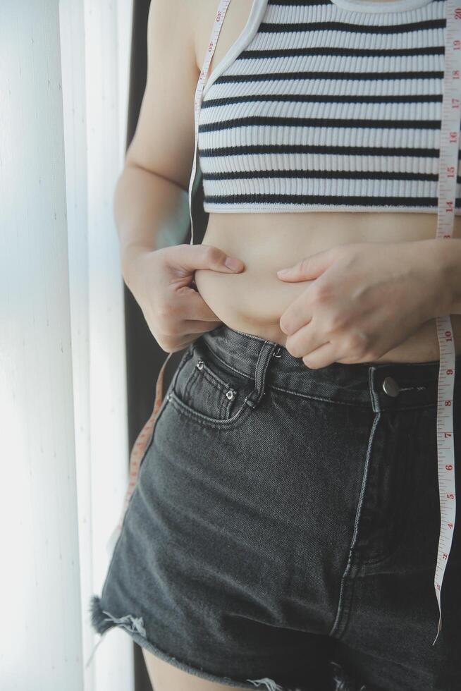 mujer cuerpo grasa barriga. obeso mujer mano participación excesivo barriga gordo. dieta estilo de vida concepto a reducir barriga y forma arriba sano estómago músculo. foto