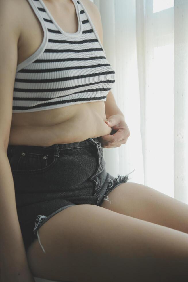 mujer cuerpo grasa barriga. obeso mujer mano participación excesivo barriga gordo. dieta estilo de vida concepto a reducir barriga y forma arriba sano estómago músculo. foto