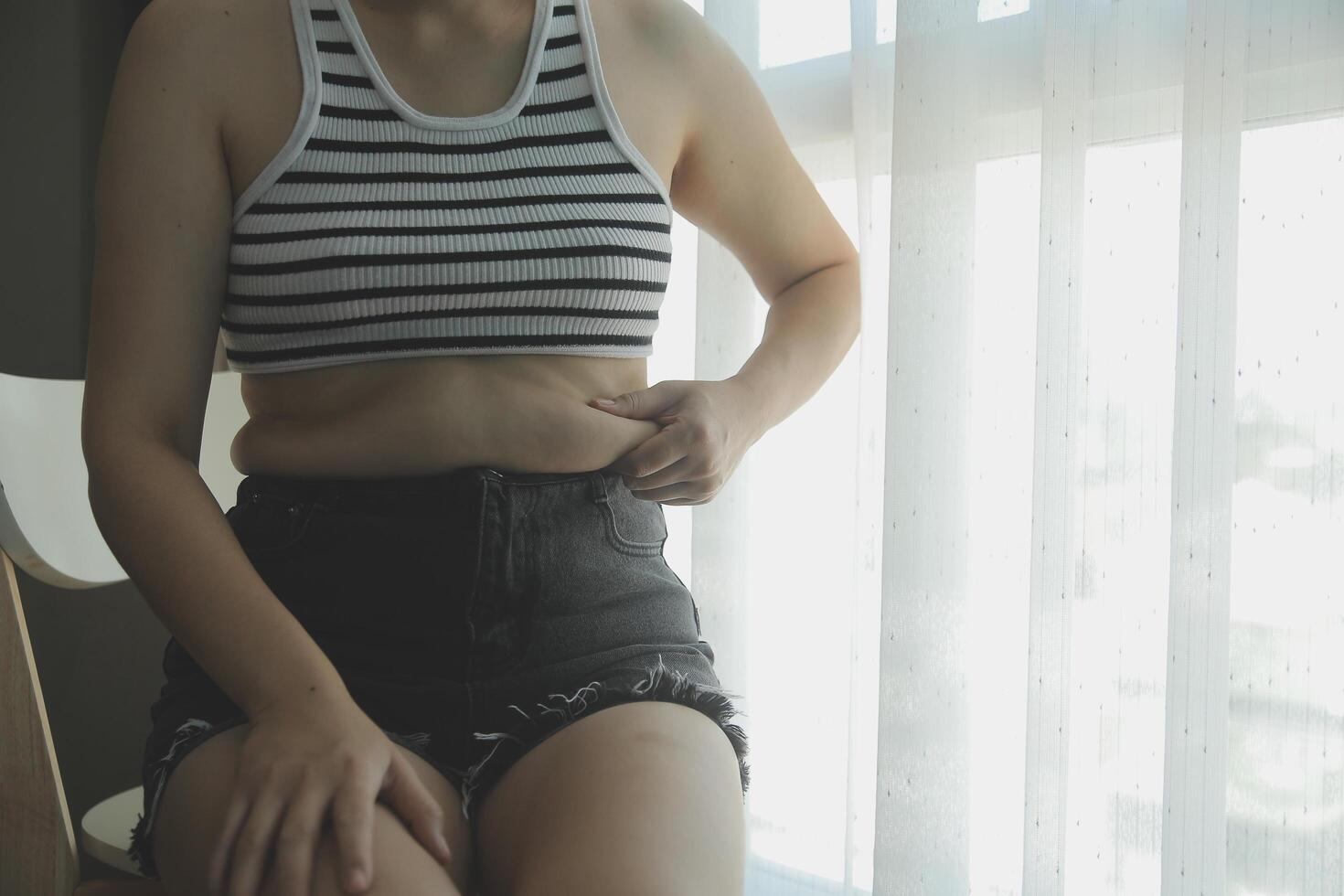 mujer cuerpo grasa barriga. obeso mujer mano participación excesivo barriga gordo. dieta estilo de vida concepto a reducir barriga y forma arriba sano estómago músculo. foto