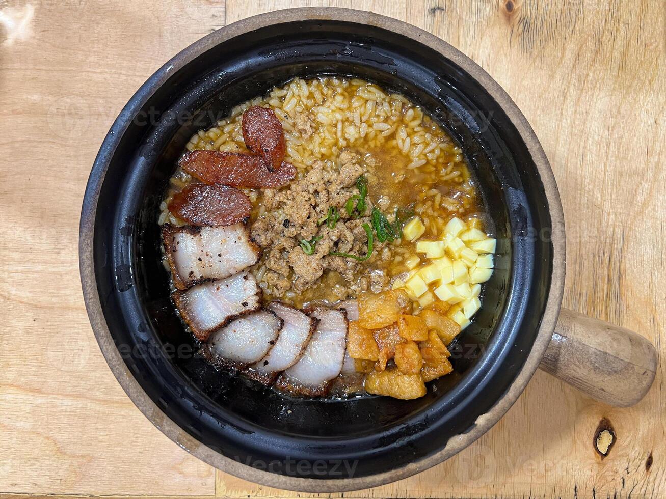 Claypot Rice, Rice cooked inside hot claypot served with crispy pork belly, pork sausages, minced meat, tofu and savory soup photo