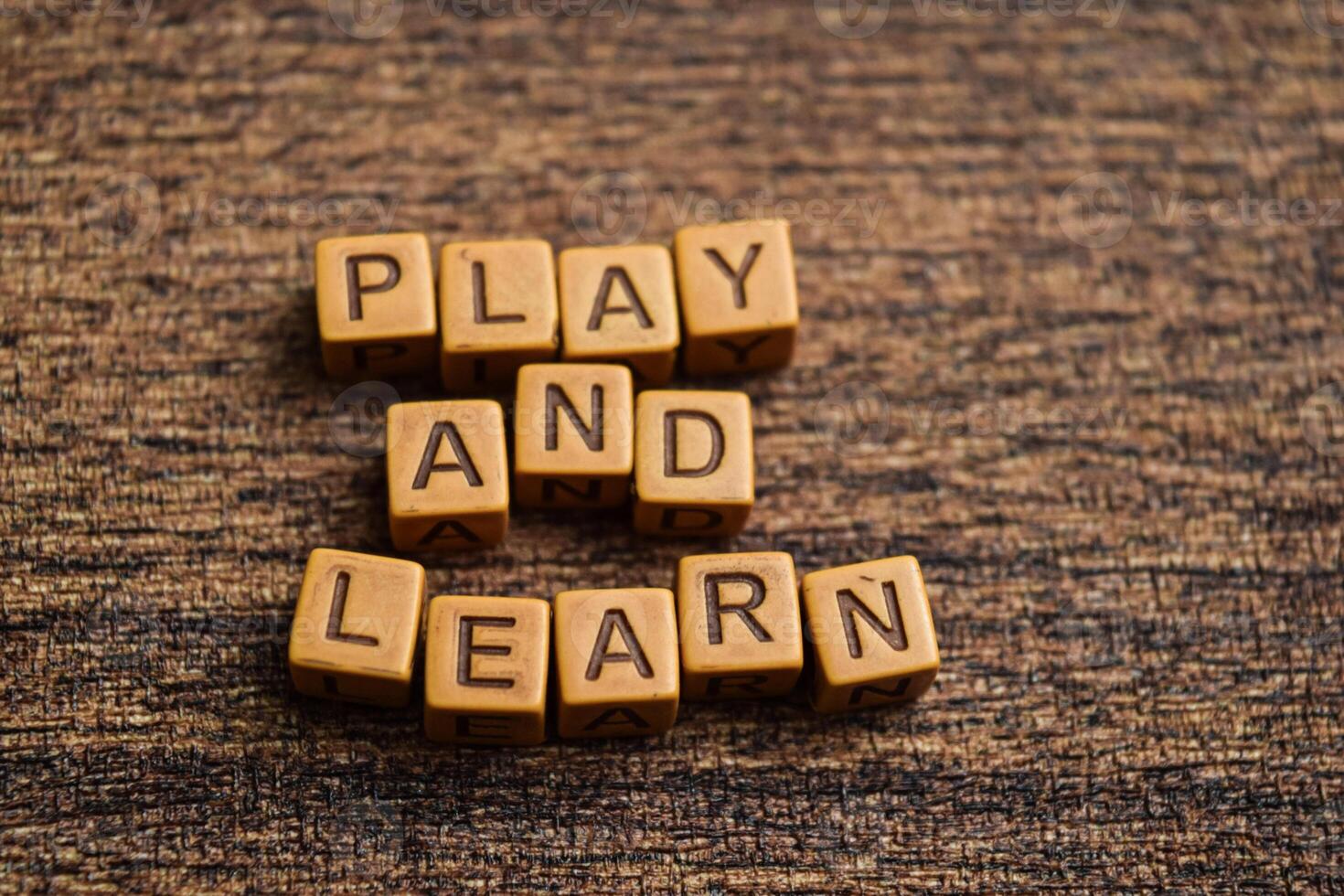 Concept of Play and Learn message written on wooden blocks. Cross processed image on Wooden Background photo