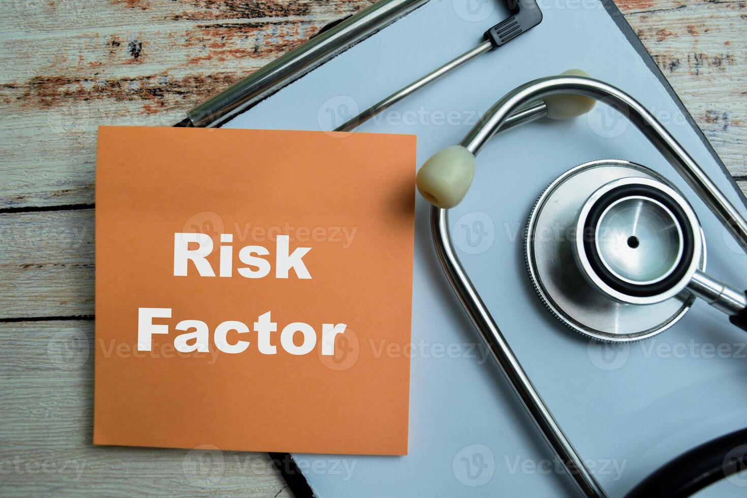Concept of Risk Factor write on sticky notes with stethoscope isolated on Wooden Table. photo