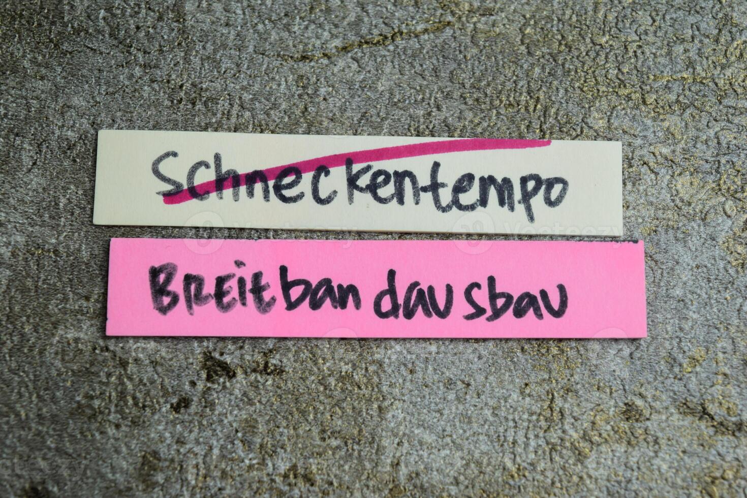 Concept of Learning language - German. Schneckentempo breitbandausbau it means Broadband expansion at a snail's pace written on sticky notes. German language isolated on Wooden Table. photo