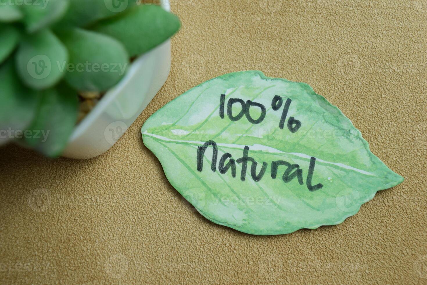 Concept of 100 percent Natural write on sticky notes isolated on Wooden Table. photo