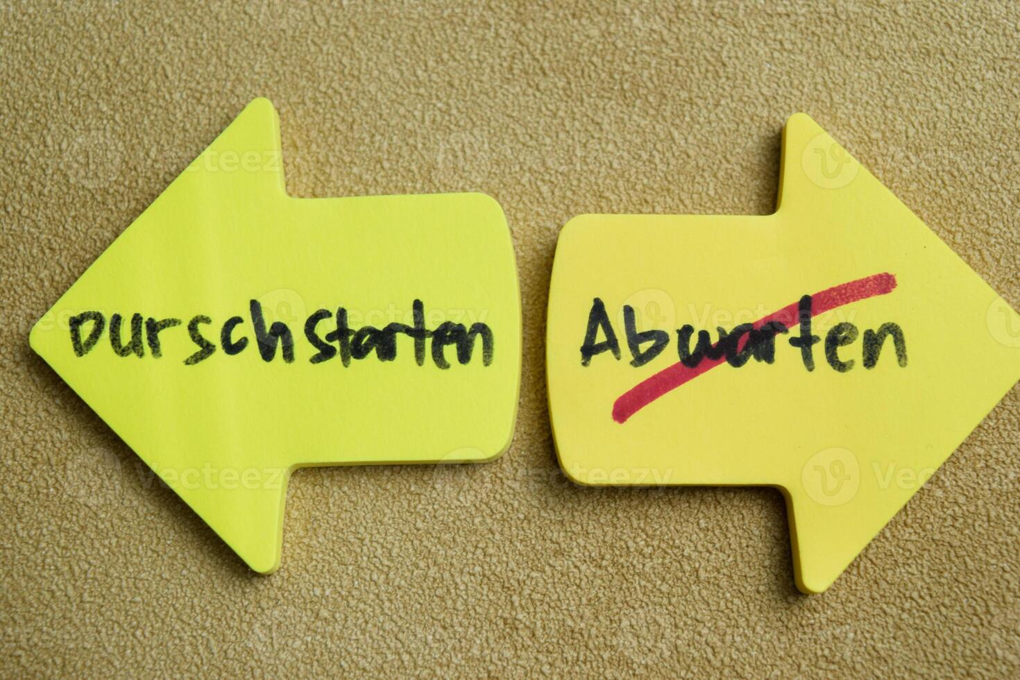 Concept of Durschstarten or Abwarten write on sticky notes isolated on Wooden Table. photo