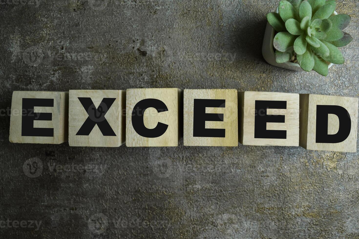 Concept of The wooden Cubes with the word Exceed on wooden background. photo
