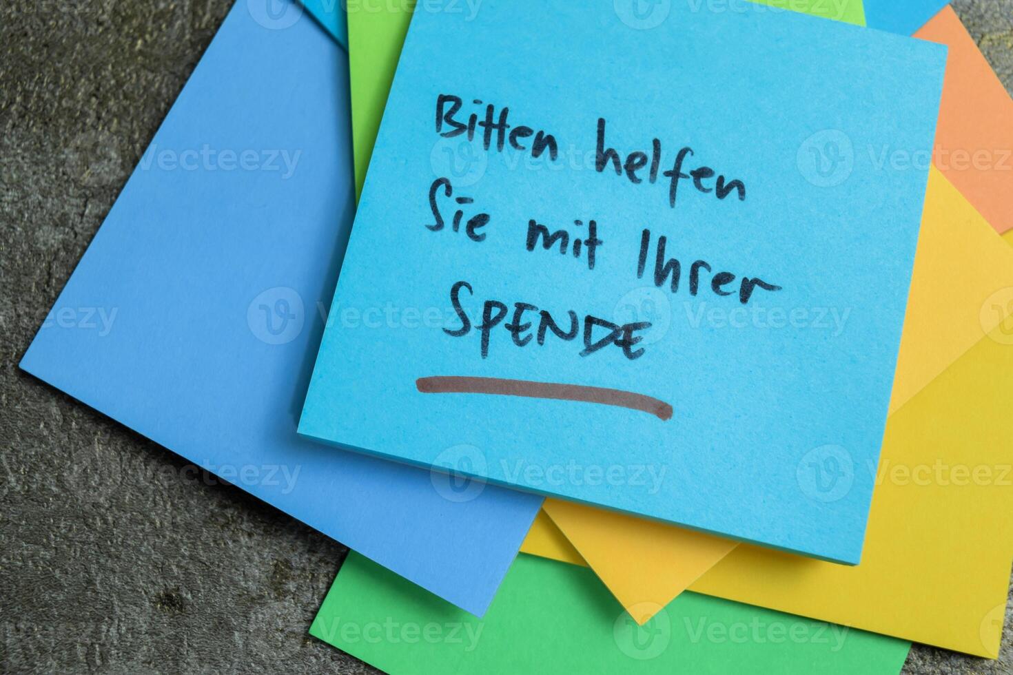 Concept of Learning language - German. Bitten Helfen Sie mit ihrer Spende it means Please help with your donation written on sticky notes. German language isolated on Wooden Table. photo