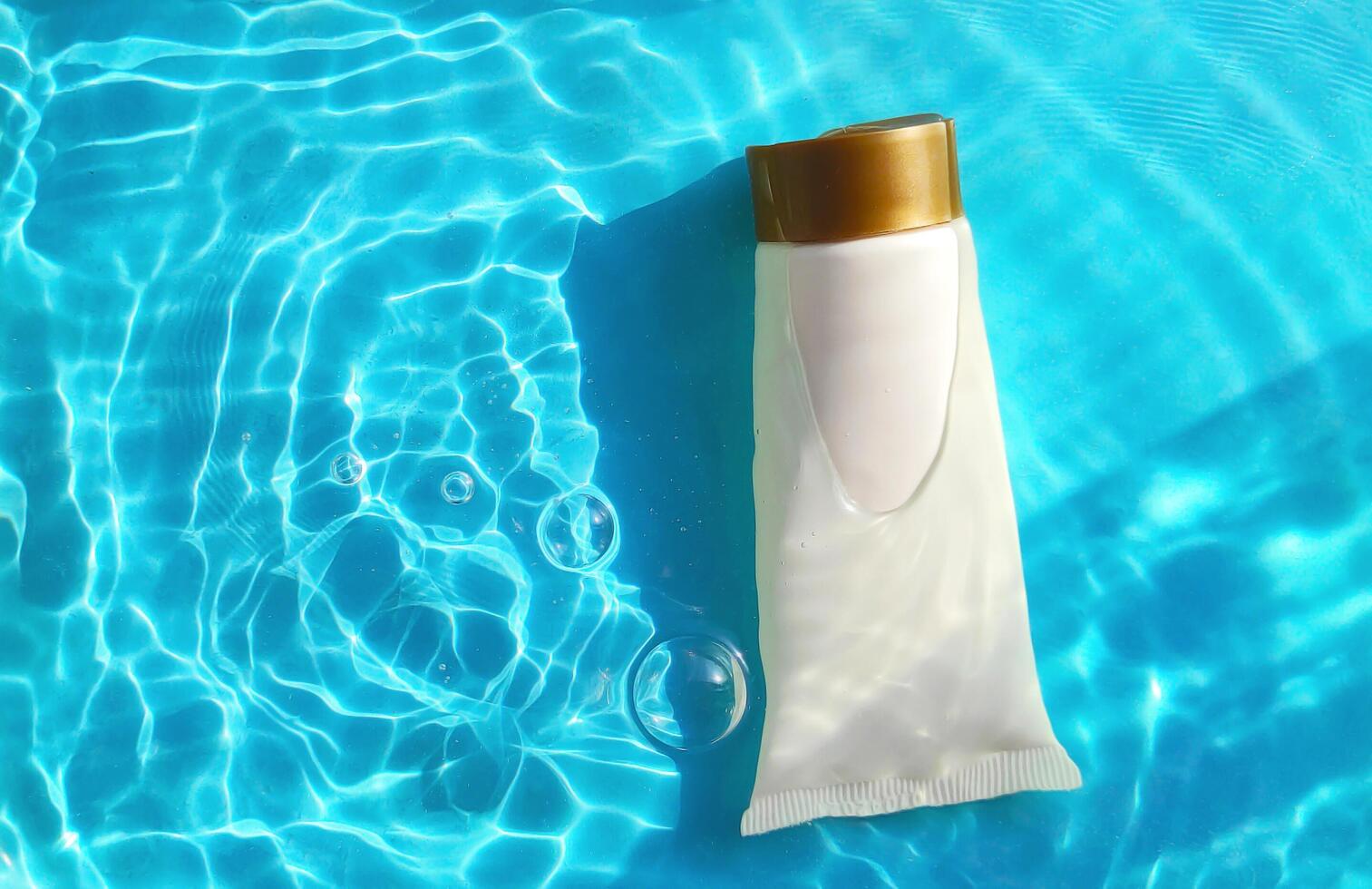 Mock up tube with cosmetic product for moisturizing in water on blue background. Template for design photo