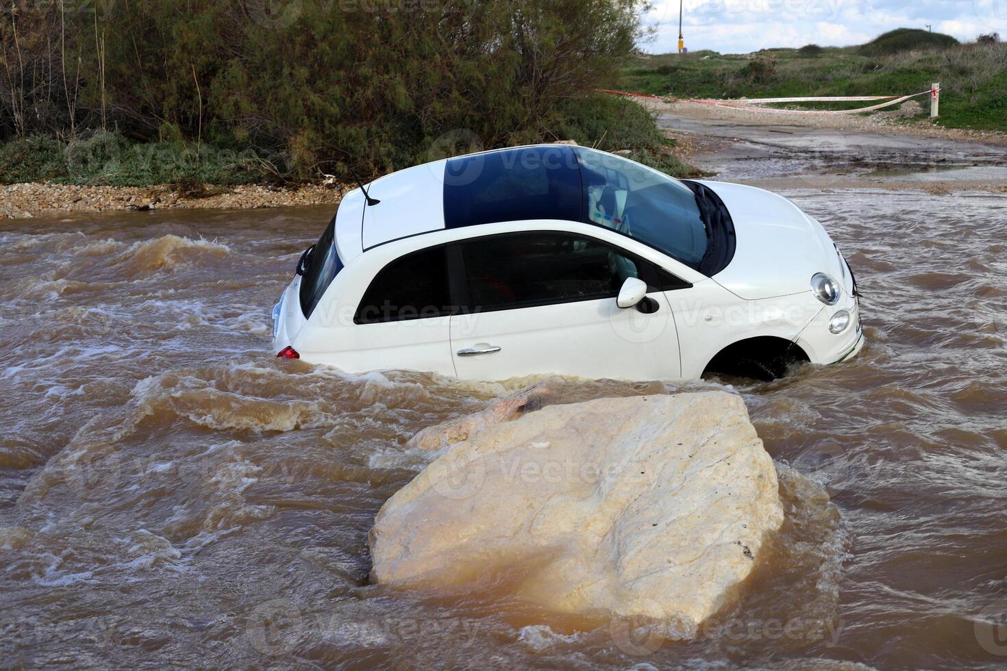 The car was carried away by a strong rain flow of water. photo