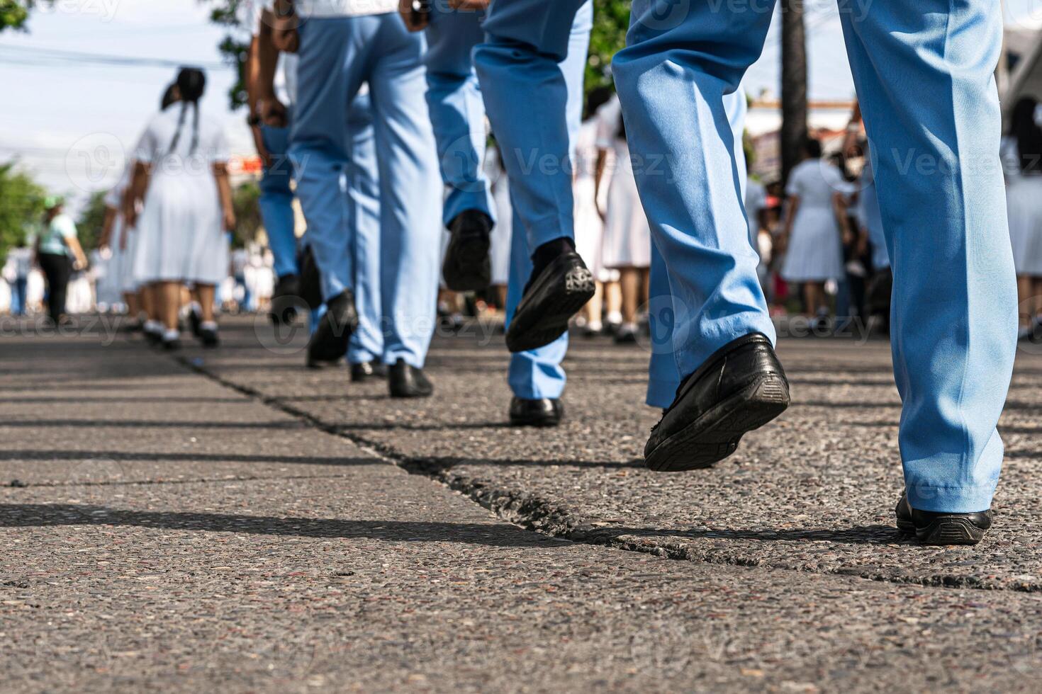 Feet of uniformed men and women marching in a parade on the street. photo