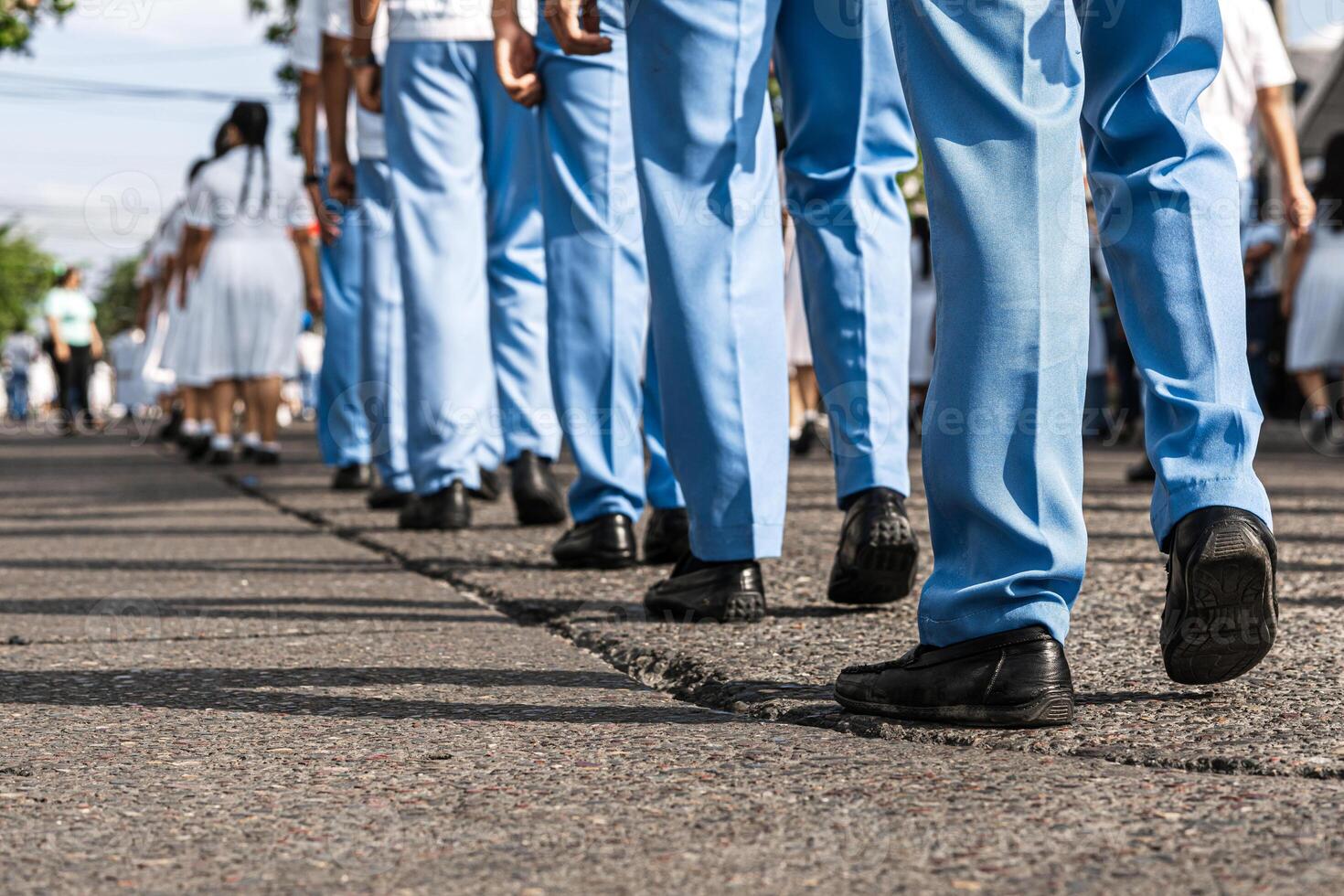 Feet of uniformed men and women marching in a parade on the street. photo
