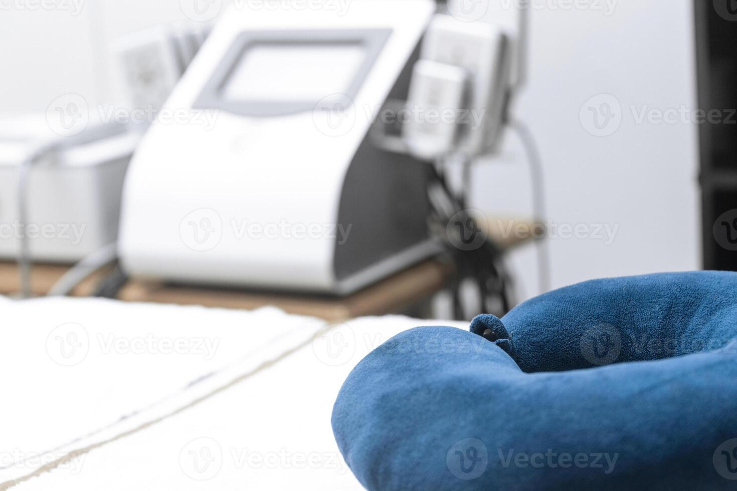 Close up of a bed with a pillow for massages and aesthetic treatments in the background a cavitation machine photo