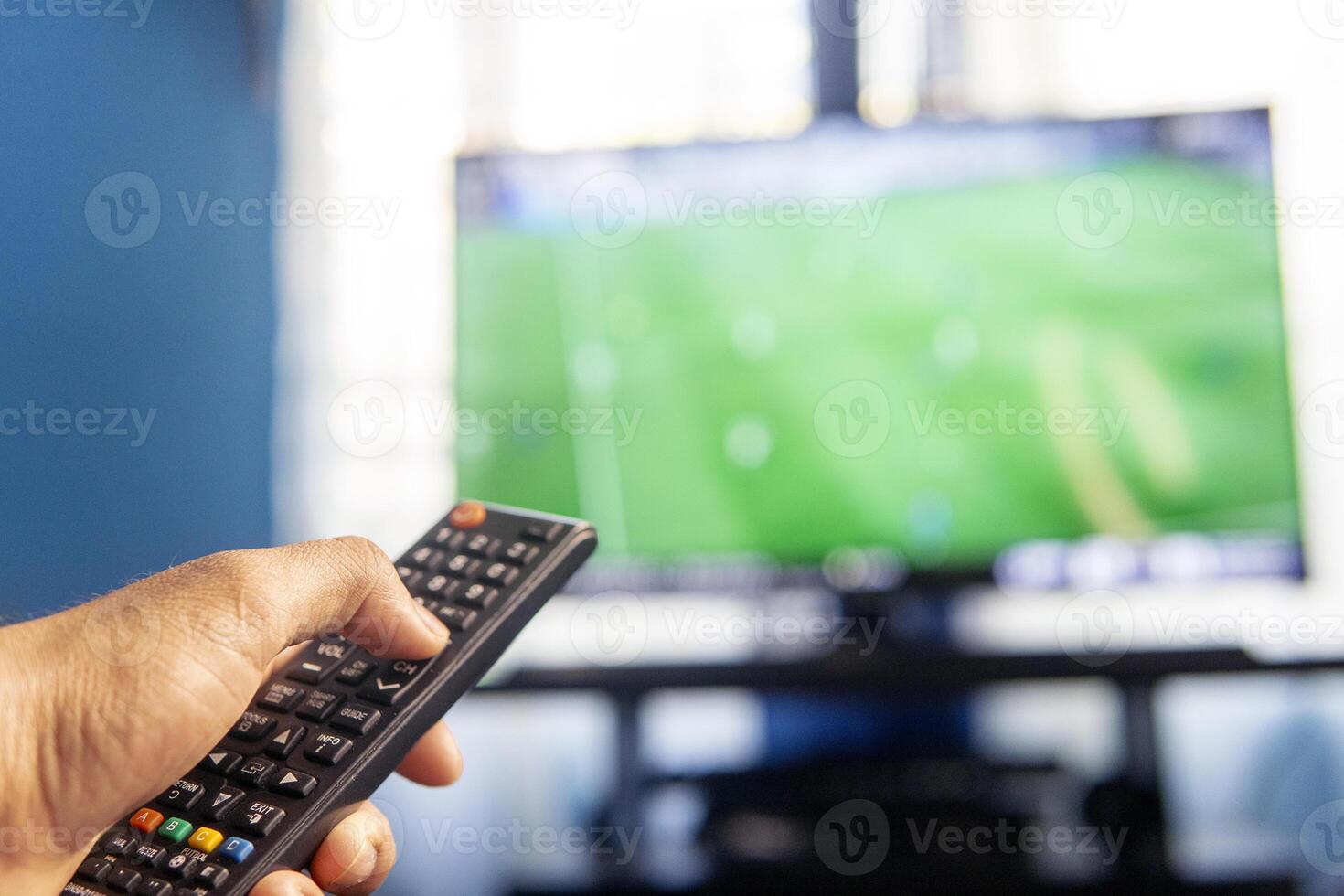 Hands holding a remote control watching a tv photo